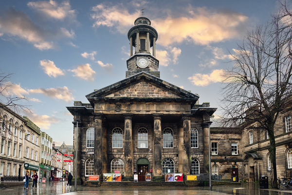 Photo of Lancaster City Museum, a stone building in classical georgian style, with columns under a triangular portico and small clock tower. 